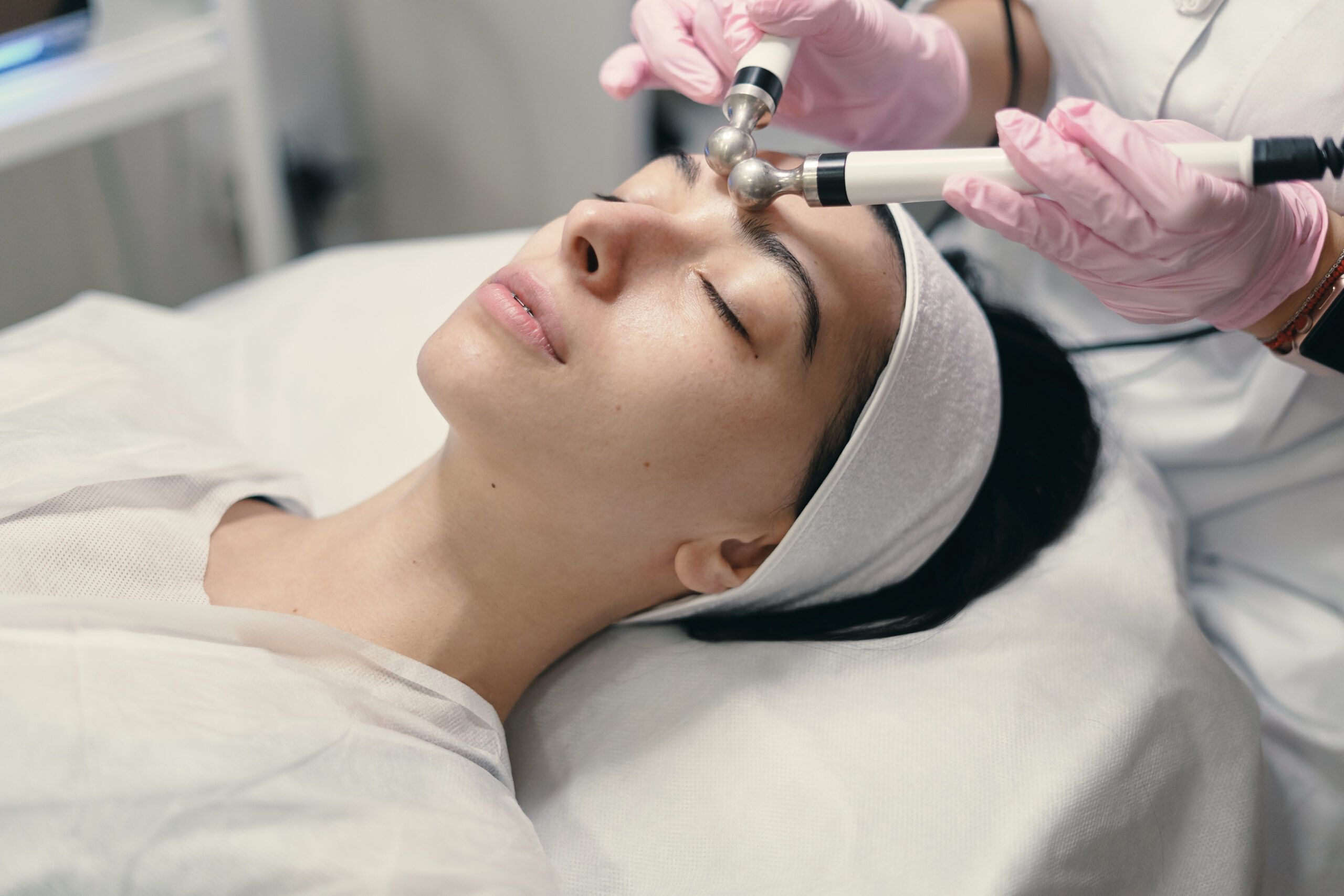 Rejuvenating facial treatment Model with closed eyes and hand's of doctor. Rejuvenating facial treatment. Model getting lifting therapy massage in a beauty SPA salon. Cosmetological clinic, procedure.